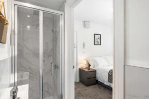 a bathroom with a glass shower and a bed at Large 6-Bed House - 5 Bathrooms w Free Parking by StaySejour in Sompting