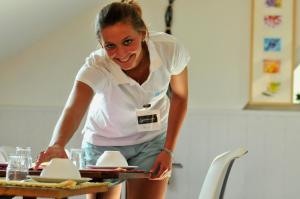 a woman holding a tray of food on a table at Résidence Goélia Les Portes d'Étretat in Maniquerville