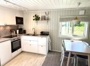 a kitchen with white cabinets and a table and a window at Brissundsbyn in Visby