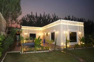 a white house with lights in a yard at Angad Farms in Kharar