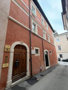 a brown building with a wooden door on a street at Dimora Piazza Palazzo in LʼAquila