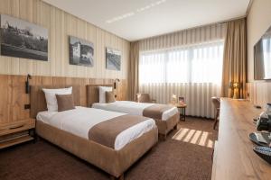 a hotel room with two beds and a desk at Hotel Le 830 Namur in Namur