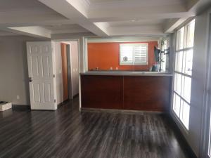 an empty room with a kitchen with wood floors and windows at LYFE INN & SUITES by AGA - LAX Airport in Inglewood