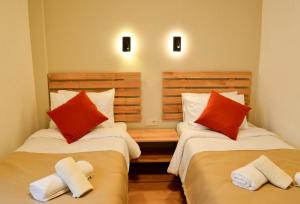 two beds in a room with red and white pillows at Kale Otel Bodrum in Bodrum City