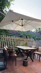 a picnic table with an umbrella next to a fence at 喜悦民宿 Joy in Luang Prabang