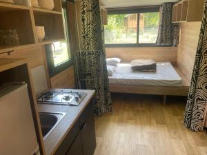 a small kitchen with a bed in a tiny house at Camping Onlycamp les Cochards in Seigy