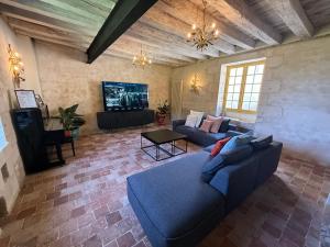 a living room with a blue couch and a tv at Gîte du Château des Brétignolles - Patrimoine, Piscine & Nature - Près de Chinon in Anché