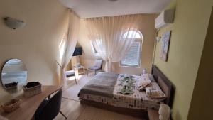 a bedroom with a bed and a desk and a window at Dimana in Chernomorets