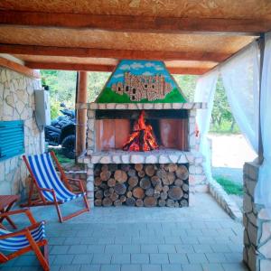 a fireplace in a patio with two chairs and a fire at Kuća za odmor Veles in Orahovica