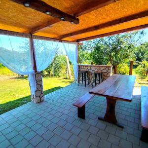 a patio with a wooden bench and a table at Kuća za odmor Veles in Orahovica