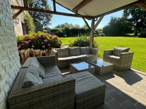 a patio with wicker couches and a table at Le gîte d’Hayen in Sprimont
