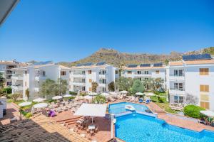 an apartment with a swimming pool and buildings at Aparthotel Flora in Port de Pollensa