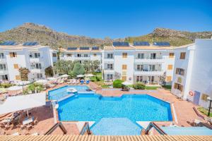 an apartment with a swimming pool in front of buildings at Aparthotel Flora in Port de Pollensa