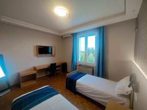 a hotel room with two beds and a desk and a window at Hotel Ristorante Oro in Cento