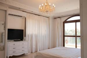 a bedroom with a bed and a tv and a chandelier at Island House in Jazīrat Aswān