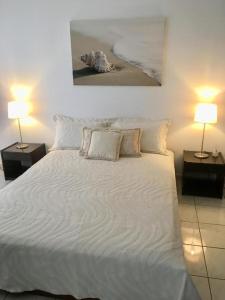 a bedroom with a white bed with two lamps at Eratous Seaside House in Varnávas +25 photos