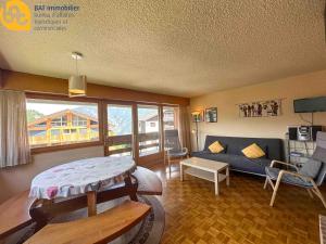 a living room with a blue couch and a living room with a couch at Scierie A Meya 118 - Appartement charmant proche des télécabines et du village in Vercorin +12 photos