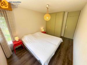 a small bedroom with a white bed and two tables at Scierie A Meya 118 - Appartement charmant proche des télécabines et du village in Vercorin