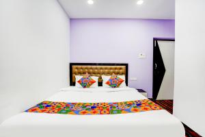 a bedroom with a white bed with colorful pillows at FabHotel Triotel Inn in Dhanbād