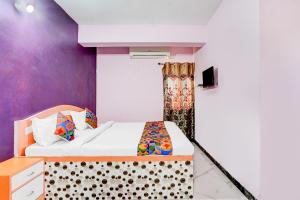 a bedroom with a bed and a purple wall at FabHotel Triotel Inn in Dhanbād