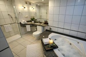 a bathroom with a tub and a toilet and a shower at Novo Santoni Hotel Guarapuava in Guarapuava