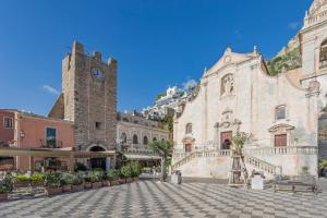 a building with a clock tower in a plaza at Paradise Residence Garden in SantʼAlessio Siculo