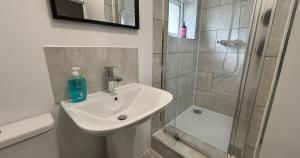 a white bathroom with a sink and a shower at Contractor Workforce Accommodation - 5 Bedrooms Perfect For Work Crews & Groups, WiFi Smart TV's In All Rooms - Parking Sleeps 5-8 Guests in Kettering