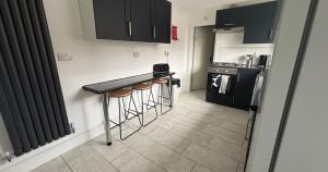 a small kitchen with a black counter and stools at Contractor Workforce Accommodation - 5 Bedrooms Perfect For Work Crews & Groups, WiFi Smart TV's In All Rooms - Parking Sleeps 5-8 Guests in Kettering