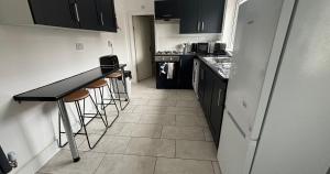 a kitchen with black cabinets and a counter and stools at Contractor Workforce Accommodation - 5 Bedrooms Perfect For Work Crews & Groups, WiFi Smart TV's In All Rooms - Parking Sleeps 5-8 Guests in Kettering