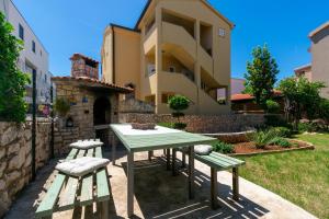 a picnic table and two benches in front of a building at Apartments Lea in Mandre