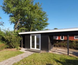 a black house with a white door in a yard at Top Modern Holiday Home 100 M From The Baltic Sea in Nordborg