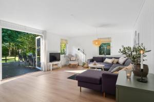 a living room with a couch and a tv at Newly Renovated And Modern Cottage Near The Beach in Hornbæk