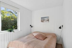 a bed in a white room with a window at Newly Renovated And Modern Cottage Near The Beach in Hornbæk
