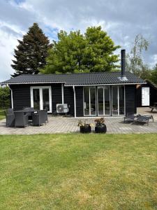a black house with a deck and a patio at Summer House Near The Sea And Good Experiences in Børkop
