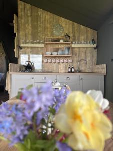 a kitchen with a table with purple and yellow flowers at Brocklands Farm Glamping in Petersfield
