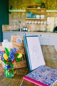a table with a book and a basket of flowers at Brocklands Farm Glamping in Petersfield