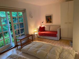 a bedroom with a bed and a couch and windows at Idyllically Situated Wooden House By The Forest in Viborg