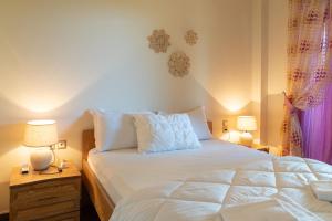 a bedroom with a bed with white sheets and two lamps at Villa Polyxeni Lavender 150m from the sea in Politika