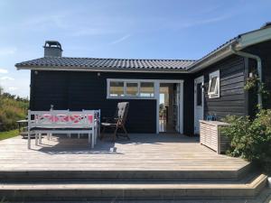 a patio with a table and a bench on a house at Nice Summer House With Sea View in Jægerspris