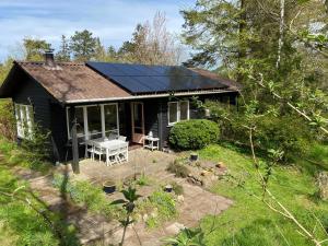 a black house with solar panels on the roof at Cottage By Veddinge In Charming 70S Style in Fårevejle