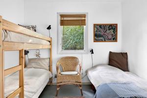 a bedroom with two bunk beds and a chair at Cottage By Veddinge In Charming 70S Style in Fårevejle