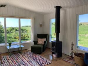 a living room with a chair and a wood stove at Peaceful Cottage By The Beach And Nature in Spottrup +19 photos