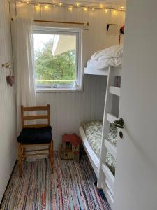 a bedroom with a bunk bed and a chair and a window at Peaceful Cottage By The Beach And Nature in Spottrup