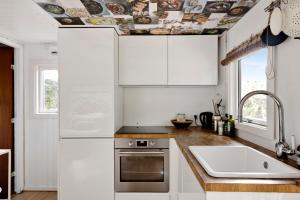 a kitchen with white cabinets and a ceiling with a sink at Charming House With Big Private Terrace in Allinge +11 photos