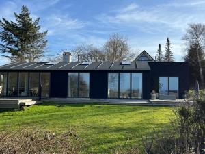 a house with solar panels on top of a yard at Unique New Beach-House I Seaview And Space in Vejby