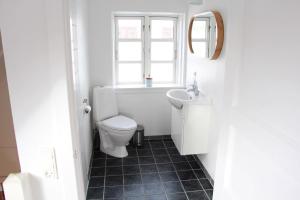 a bathroom with a toilet and a sink and a window at Summer House In Årsdale With A Beautiful Sea View in Svaneke