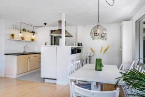a kitchen with a white refrigerator and a table at Lovely Cottage Full Of Holiday Atmosphere in Rødby