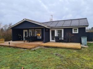 a small black house with a wooden deck at Lovely Cottage Full Of Holiday Atmosphere in Rødby