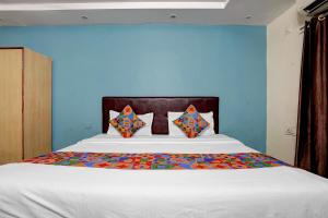 a bedroom with a large white bed with blue walls at FabHotel DP International in Patna