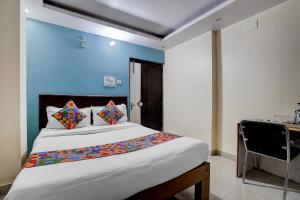 a bedroom with a large bed with a blue wall at FabHotel DP International in Patna